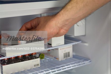 Healthcare professional removing medication vial from refrigerator