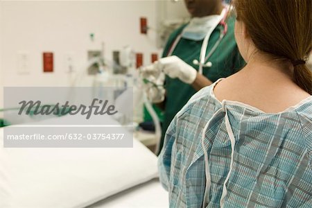 Patient watching as nurse prepares medical equipment
