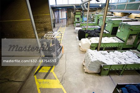 Carpet tile factory, forklift preparing fluffy fibers for processing