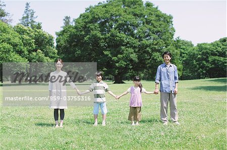 Famille debout dans un parc, main dans la main