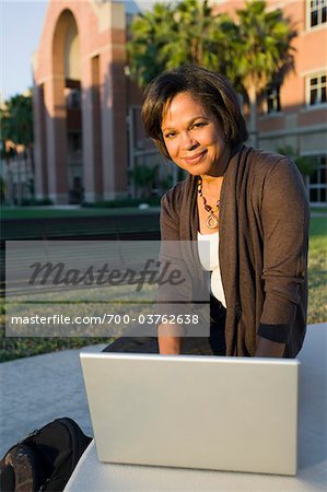 Woman Using Laptop in Front of School
