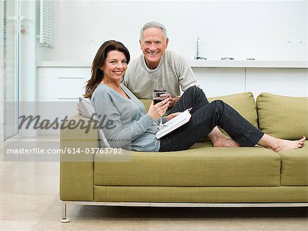 Couple d'âge mûr assis sur le canapé avec du vin