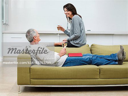 Couple d'âge mûr assis sur le canapé avec du vin