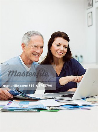 Couple d'âge mûr à l'aide d'ordinateur portable pour vacances livre