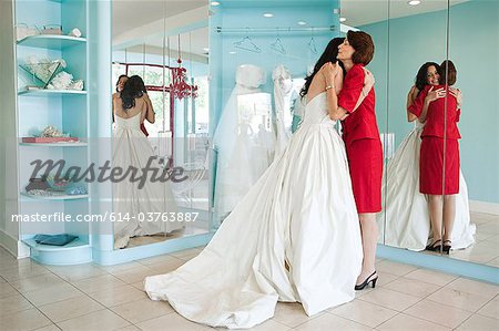 Daughter trying on wedding dress, embracing mother