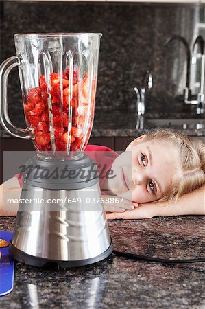 Girl looking at fruit in blender