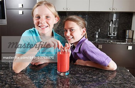 Mädchen trinken Fruchtsaft mit Strohhalmen