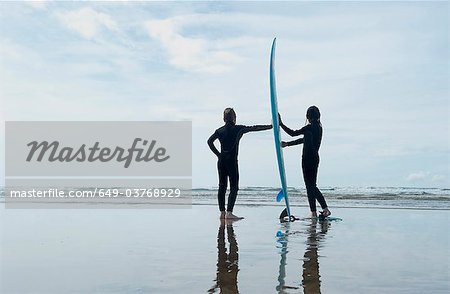 Children holding surf board on beach