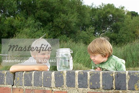 Two young boys looking at fish in a jar