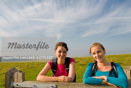 Female hikers rest on gate