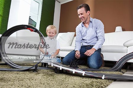 Father and son playing with race track