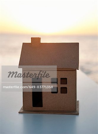 A cardboard house shot against the sea