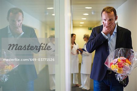 Surprised man with flowers at hospital