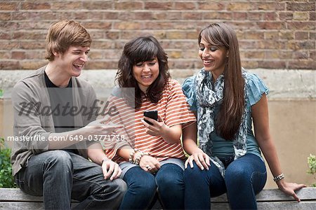 Friends sharing joke on mobile outside