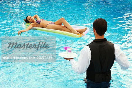 Waiter serving drinks to girl in a pool