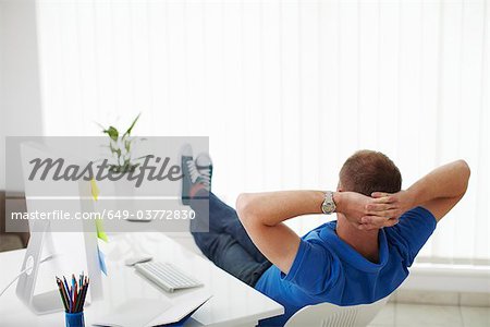 Man reclining on chair next to computer