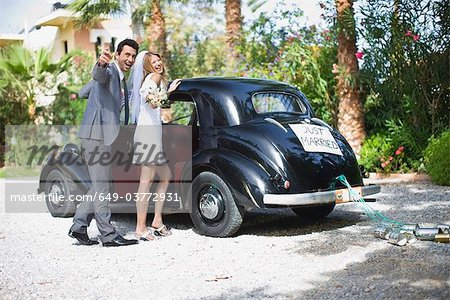 Bridal couple in front of car