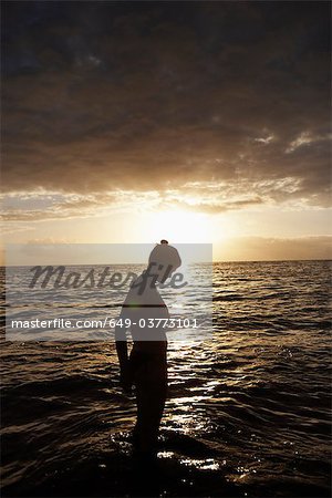 Femme debout dans la mer de crépuscule