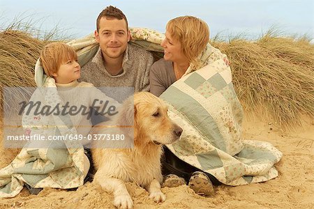 Family with dog, under quilt, on beach