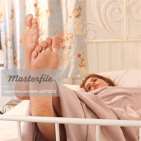 Young woman in bed with feet up