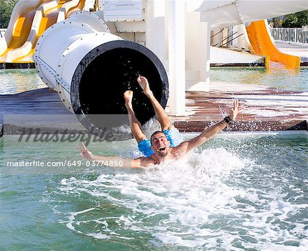 Jeune homme tombe dans la piscine de diapositive