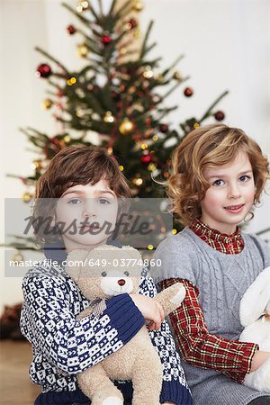 Kids with cuddly toys in front of tree