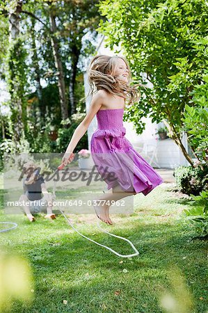 Jeune fille sautant à la corde dans le jardin
