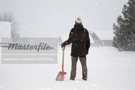 Man standing in snow with shovel