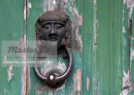 Madeira. Metal door knocker with woman's face on door with peeling green paint