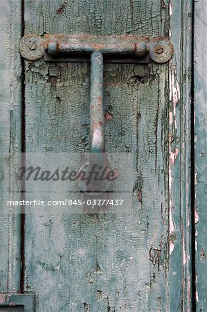 Madeira. Detail of dilapidated and rusty metal door knocker on decaying front door with peeling paint