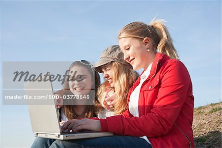 Teenagers using Laptop Outdoors