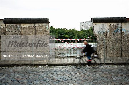 Germany, Berlin, person bicycling past dismantled section of the Berlin Wall