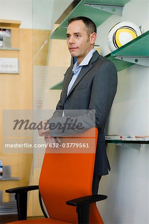 Businessman standing behind office chair, portrait