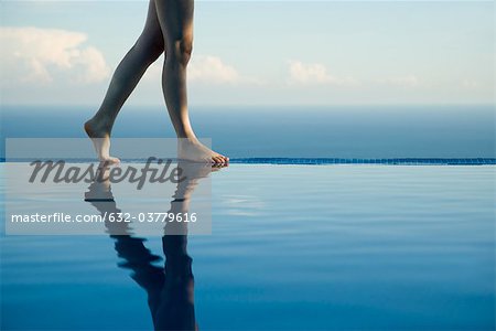 Woman walking along edge of infinity pool, low section