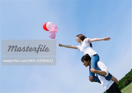 Wife Sitting on Husband's Shoulders in Park