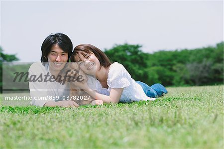Paar mit Haustieren auf Gras im Park liegen