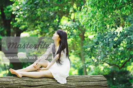 Junge Frau sitzend auf Baumstamm