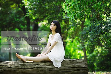 Japanese Young Woman Sitting  on Log in Forest