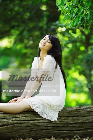 Junge Frau sitzend auf Baumstamm träumen