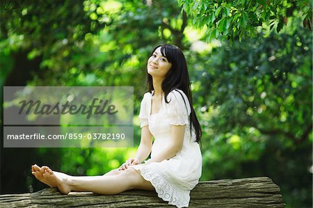 Jeune femme assise sur tronc d'arbre