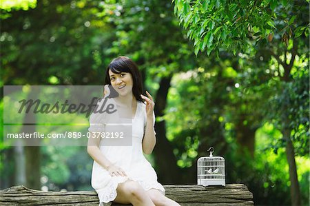 Young Woman Sitting on Tree Trunk in Forest