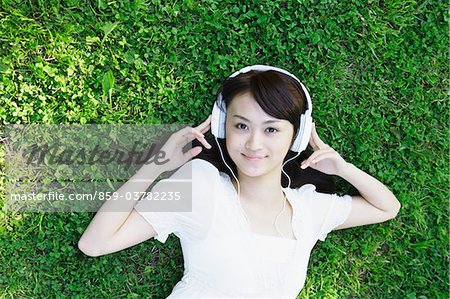 Junge Frau am Gras liegen und Musik hören