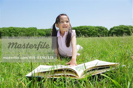 Mädchen liegend auf Gras mit Buch