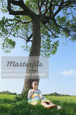 Girl Sitting in Park and Licking Lollipop