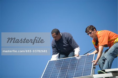 Zwei Männer heben einen großen Sonnenkollektor