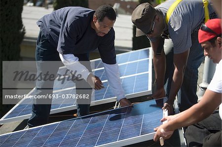 Un groupe d'hommes soulevant un grand panneau solaire