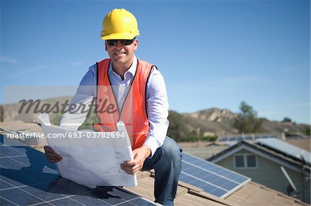 Un homme d'affaires sur un toit solaire panalled regardant des plans