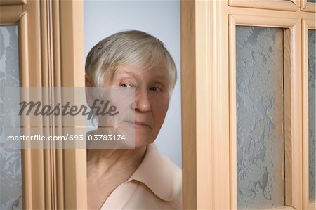Vieille femme aux cheveux gris courts, ouvrant la porte d'entrée Vieille femme aux cheveux gris courts, ouvrant la porte d'entrée