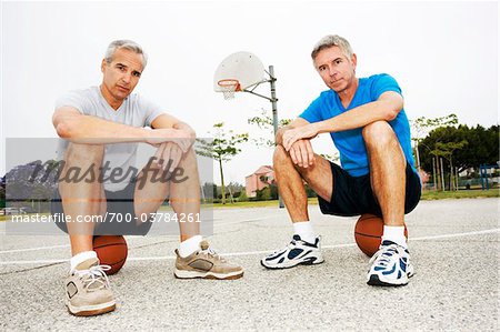 Zwei Männer sitzen auf Basketbälle auf Basketballplatz