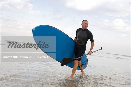 Paddle Boarder marchant sur la plage
